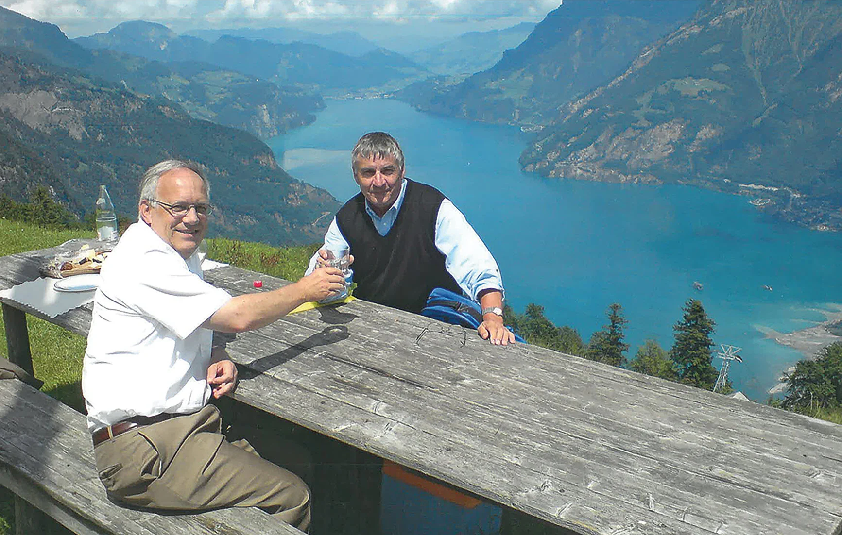Historische Aufnahme zweier Unternehmer mit Blick auf einen Schweizer Bergsee