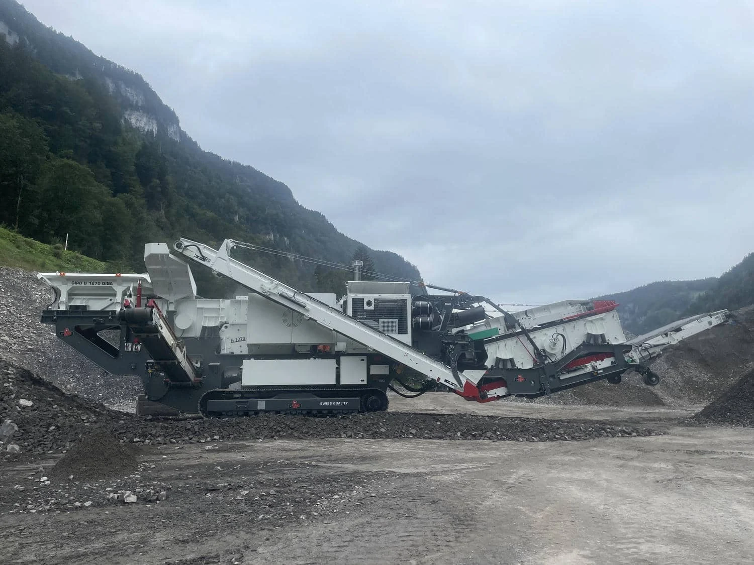Mobile Brechanlage im Einsatz im Kies- und Felsbereich, mit Förderbändern in Arbeitsposition.