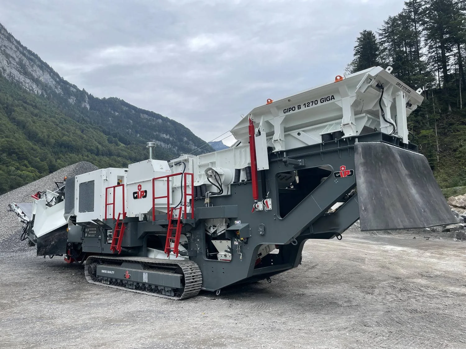 Detailansicht des raupenmobilen Backenbrechers mit aufgerichtetem Aufgabetrichter und Seitenaustrag.