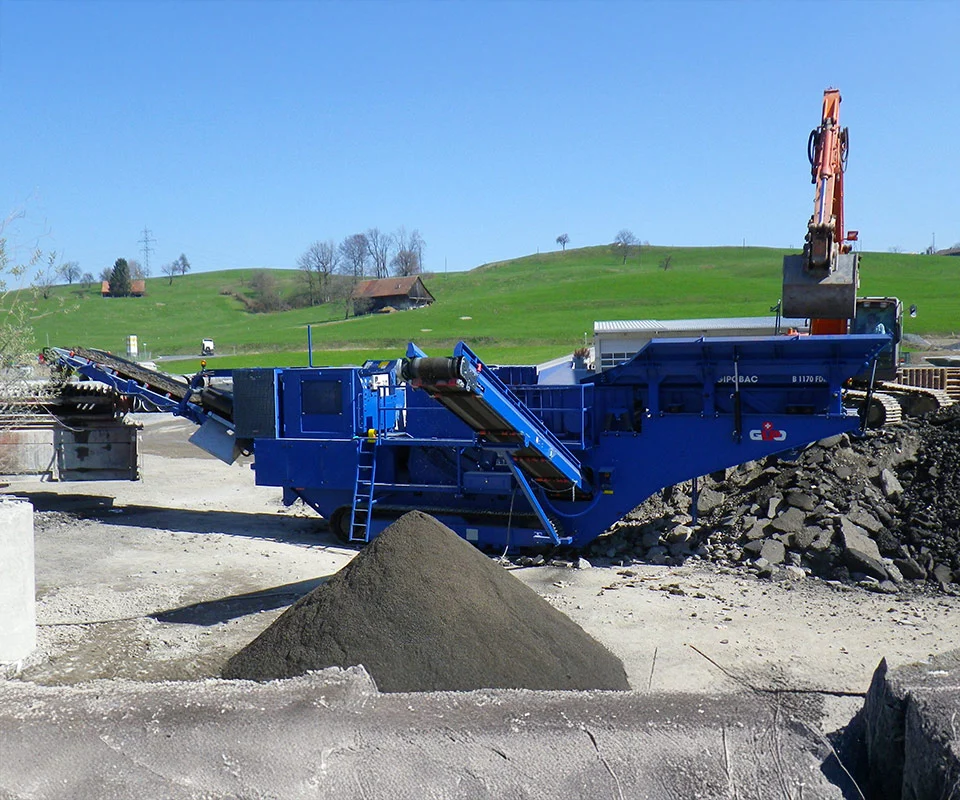 Gipo B1170 Mobile jaw crushing plant in a quarry, excavator feeding the hopper; conveyors stockpiling crushed rock