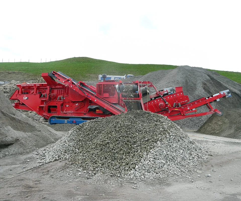 Gipo B1170 Mobile jaw crushing plant on tracks, processing blasted rock; discharge conveyors forming piles.