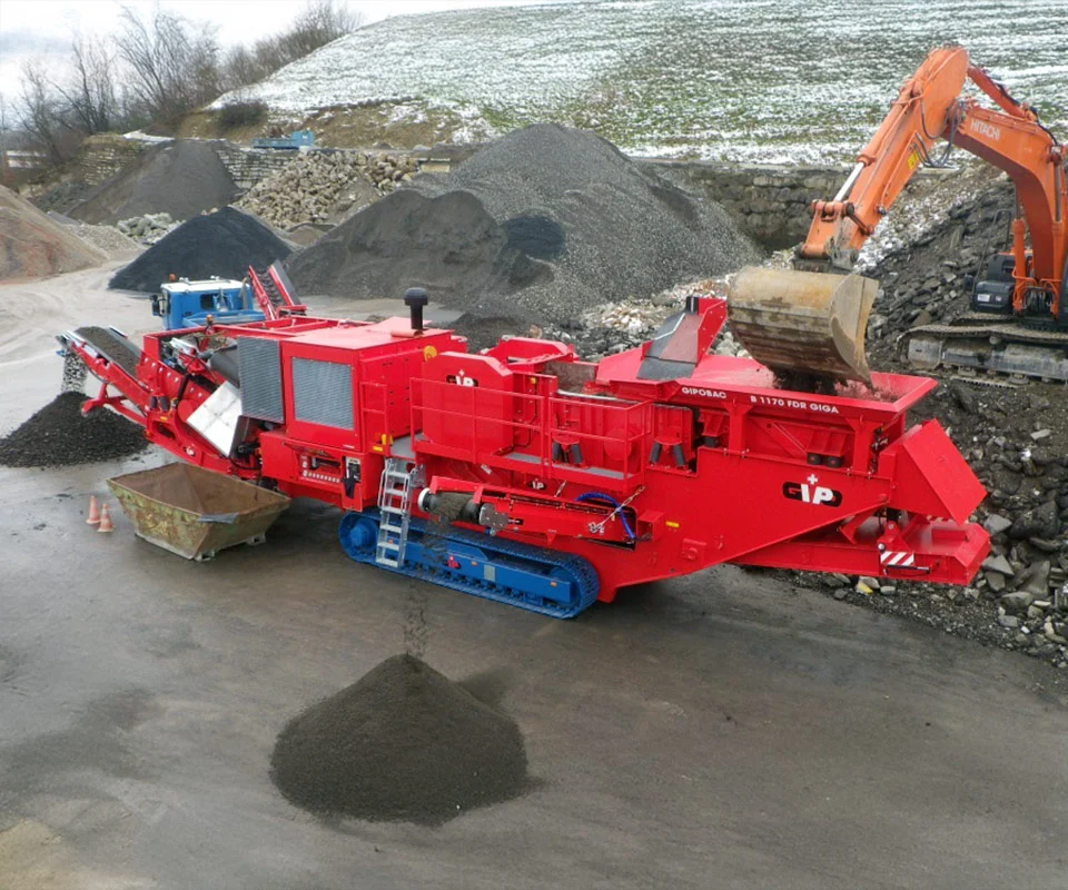 Gipo B1170 Mobile jaw crushing plant working against the quarry face; side conveyor discharging aggregate.