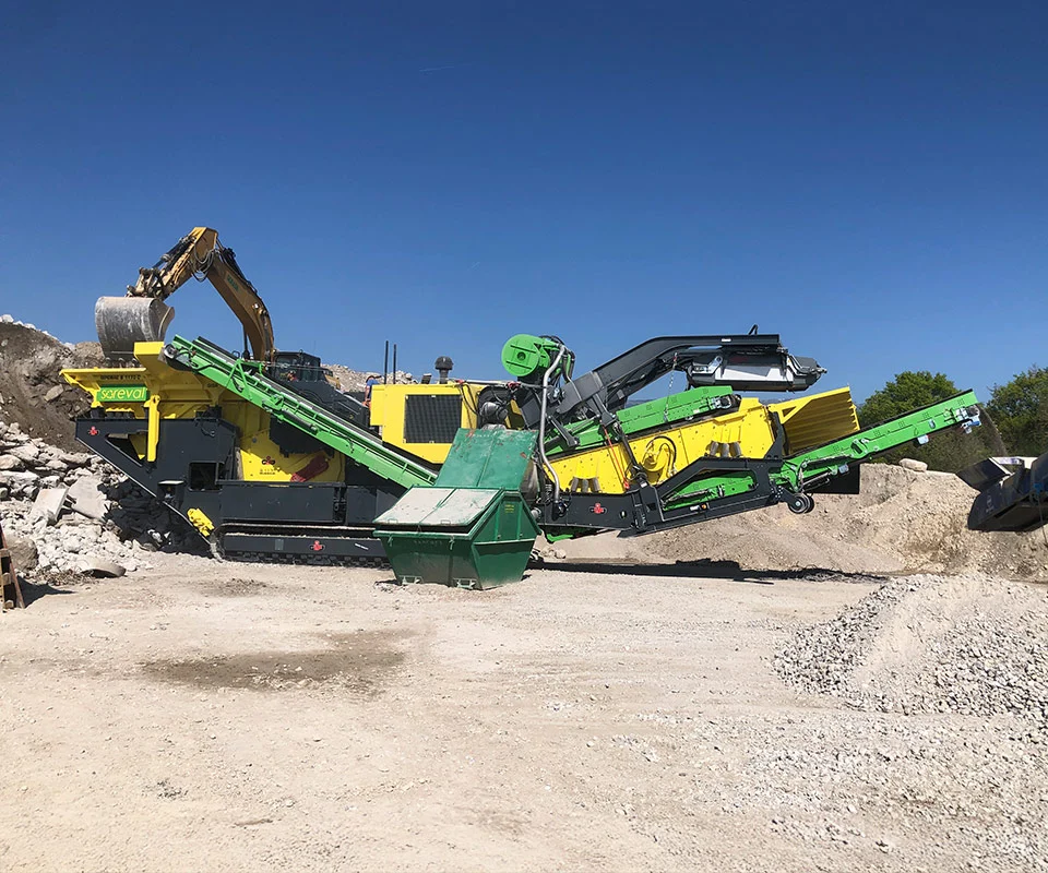 Gipo B1170 Mobile jaw crushing plant on tracks, processing blasted rock; discharge conveyors forming piles.