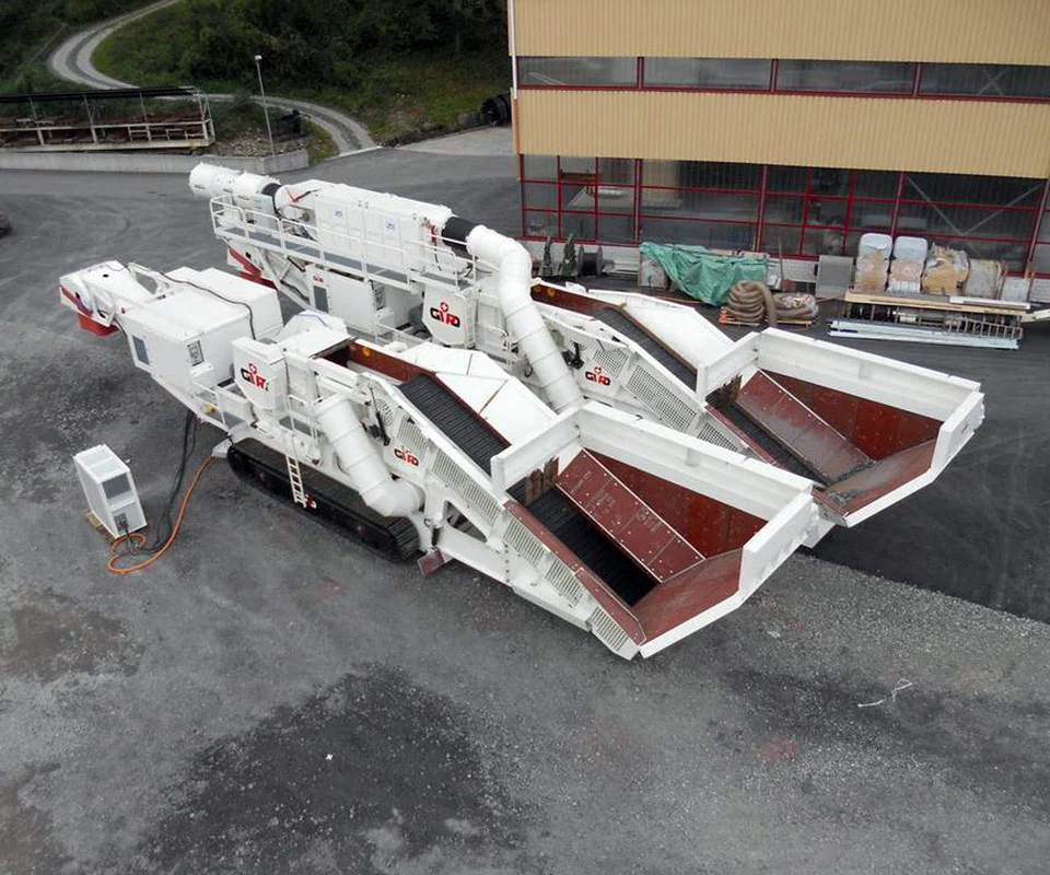 Gipo B1290 Mobile jaw crushing plant working against the quarry face; side conveyor discharging aggregate.