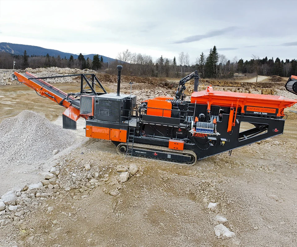 Gipo B1290 Mobile jaw crushing plant working against the quarry face; side conveyor discharging aggregate.