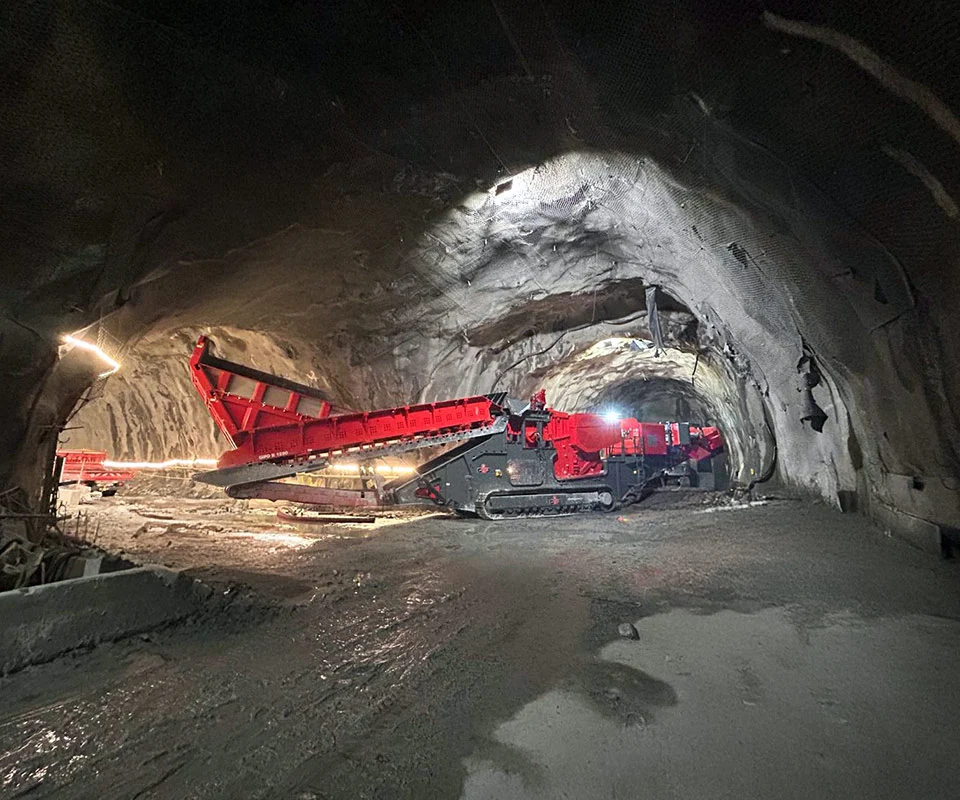 Gipo B1290 Mobile jaw crushing plant on tracks, processing blasted rock; discharge conveyors forming piles.