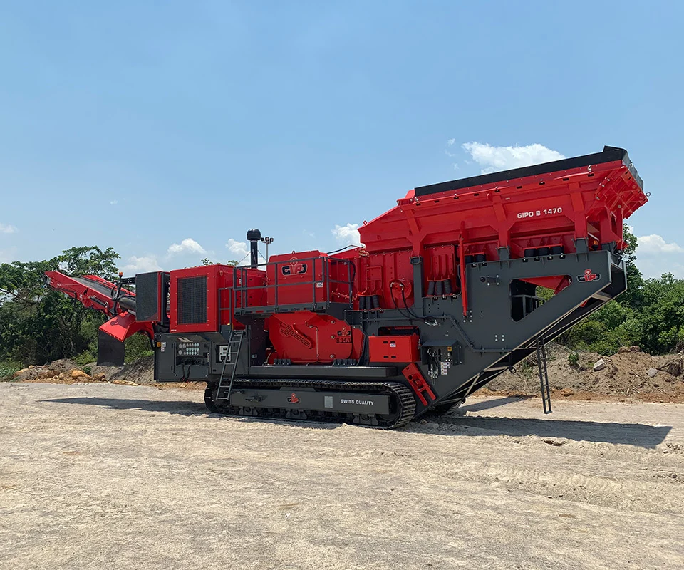 Gipo B1470 Mobile jaw crushing plant on tracks, processing blasted rock; discharge conveyors forming piles.