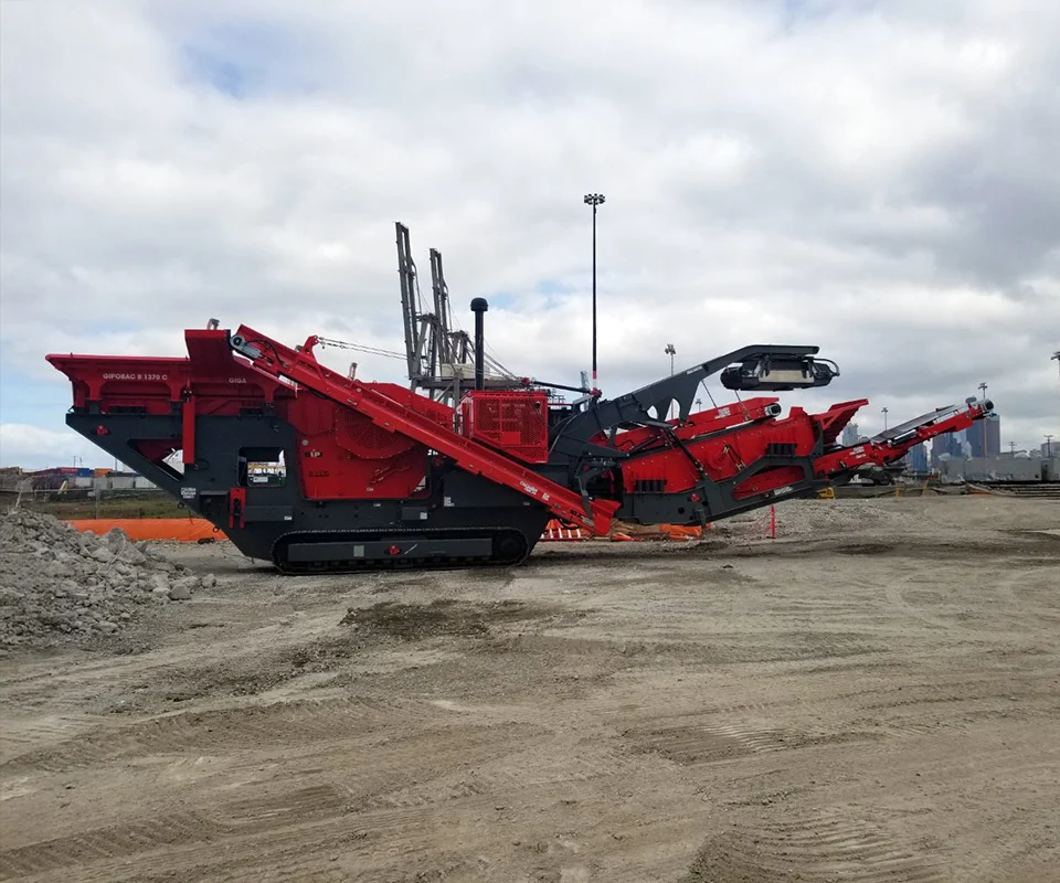 Gipo B1470 Mobile jaw crushing plant working against the quarry face; side conveyor discharging aggregate.