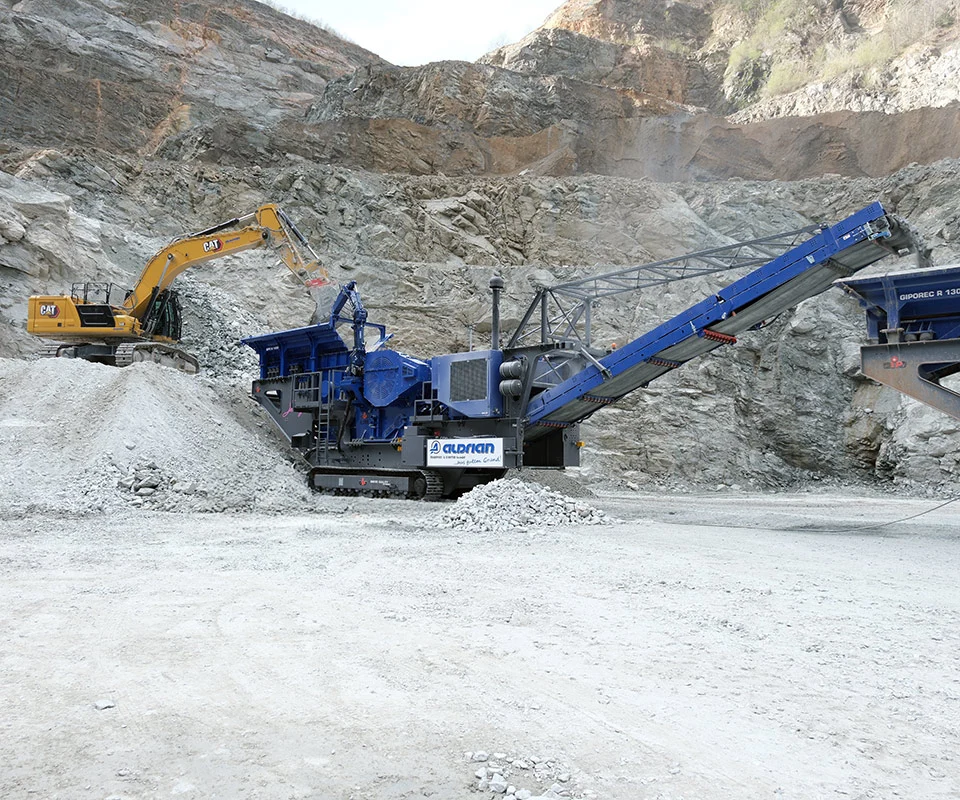 Gipo B1490 Mobile jaw crushing plant working against the quarry face; side conveyor discharging aggregate.