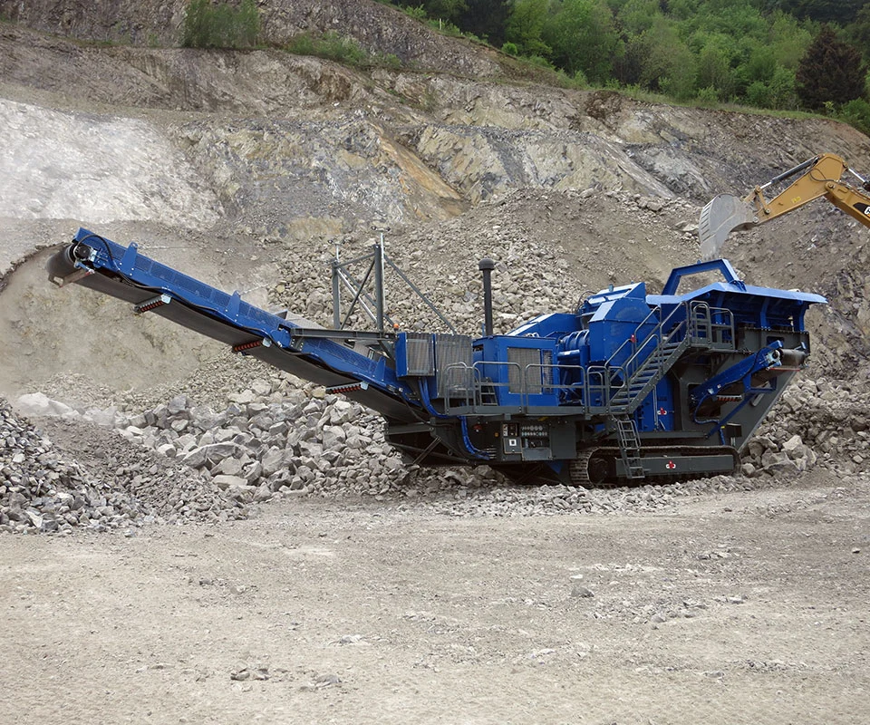 Gipo B1490 Mobile jaw crushing plant working against the quarry face; side conveyor discharging aggregate.