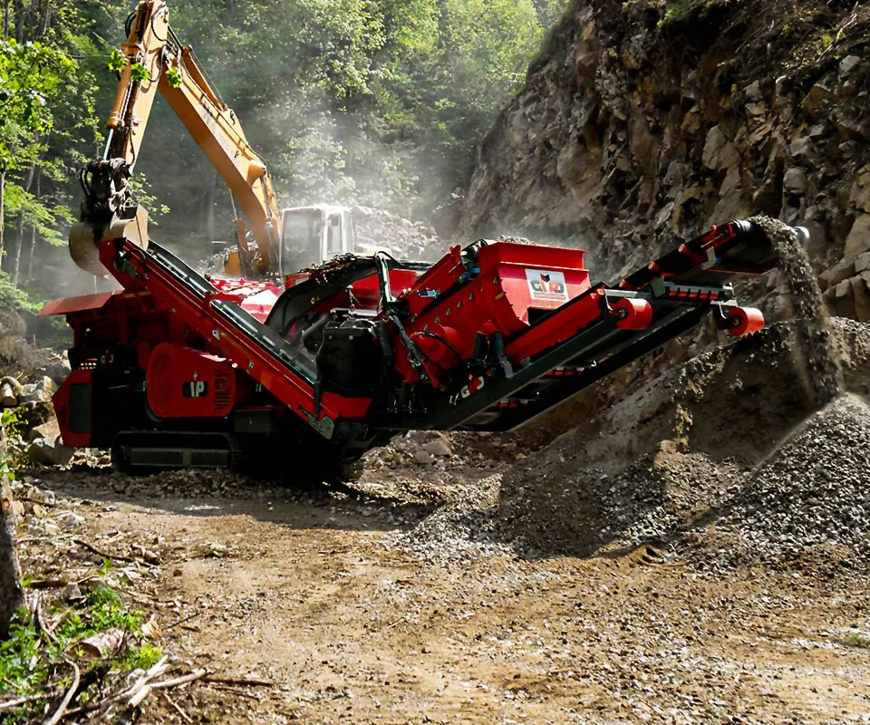 Gipo P090 Giga Concasseur à percussion mobile GIPO en carrière, alimenté par pelle; convoyeurs formant des tas de granulats.