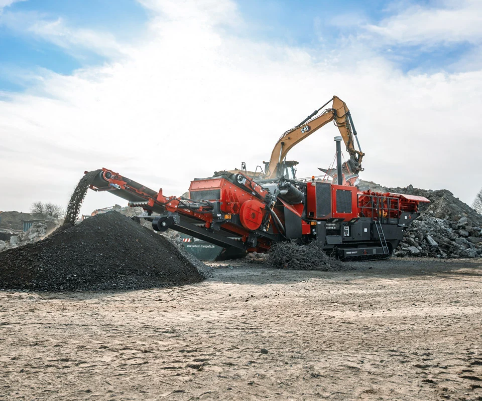 Gipo P101 Giga GIPO mobile Prallbrechanlage im Steinbruch, vom Bagger beschickt; Förderbänder bilden Halden aus gebrochenem Gestein.